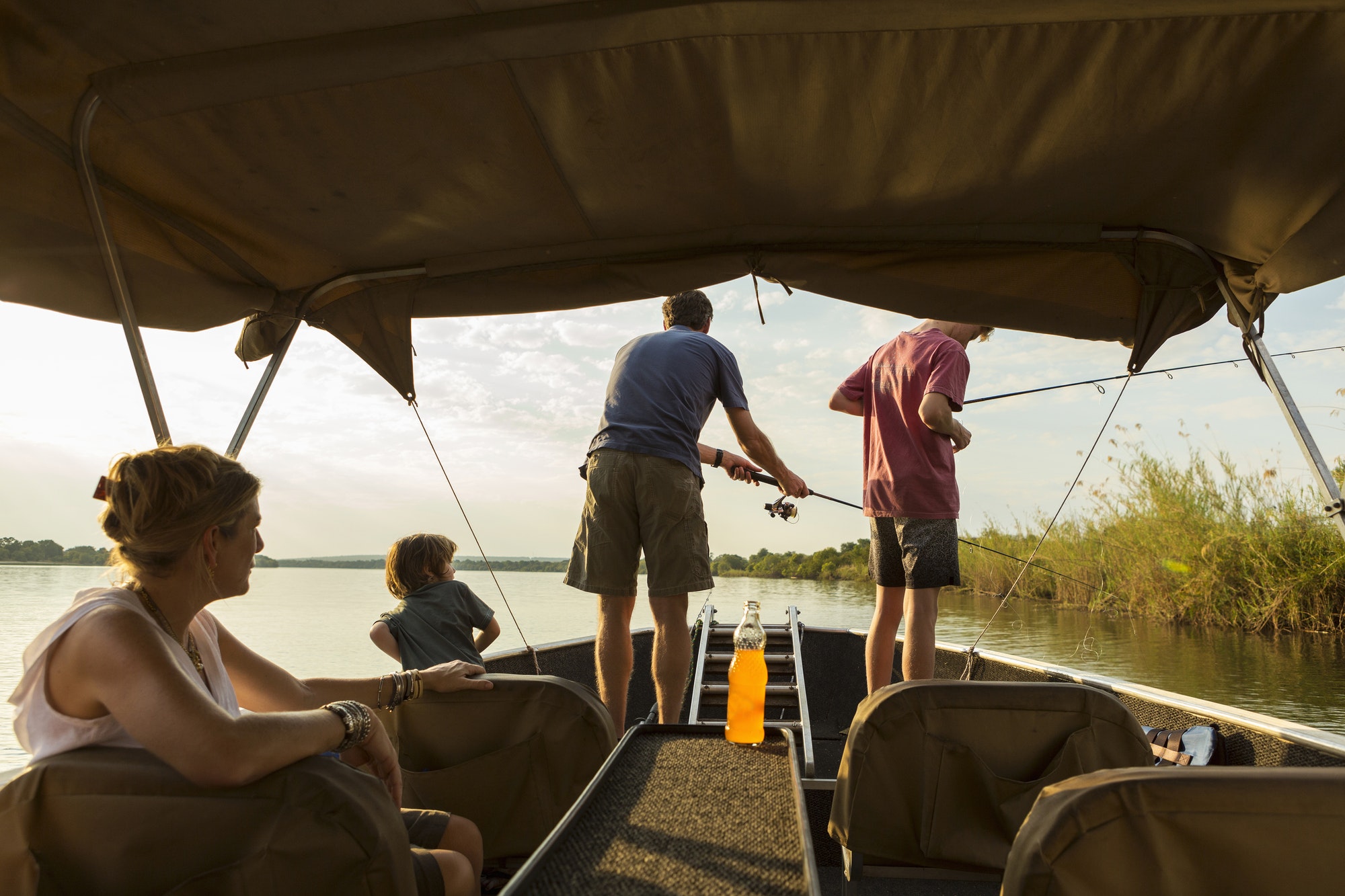 A group of tourists, family fishing from a boat on the Zambezi River, Botswana