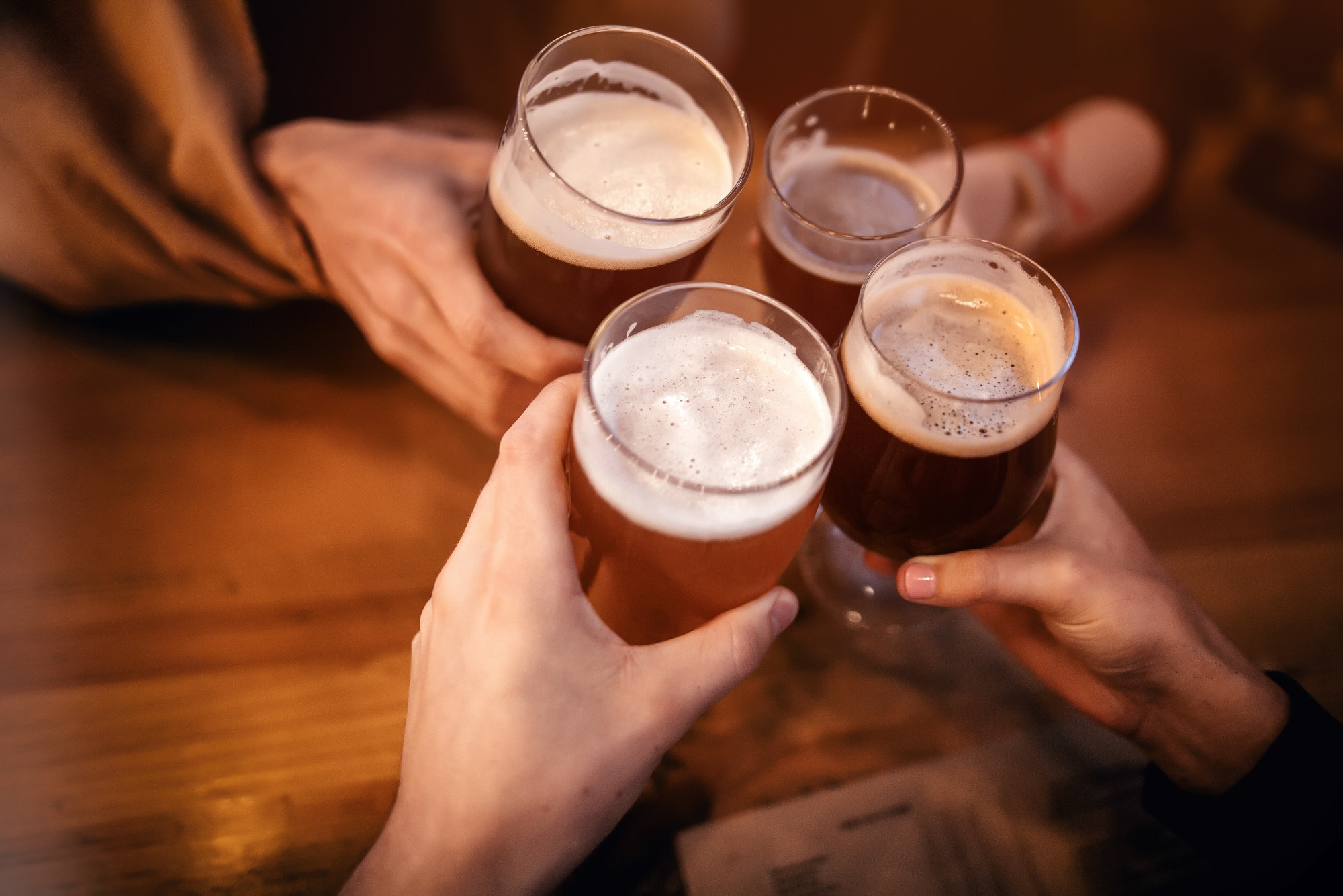 hands of people holding beer and cheering in brewery pub